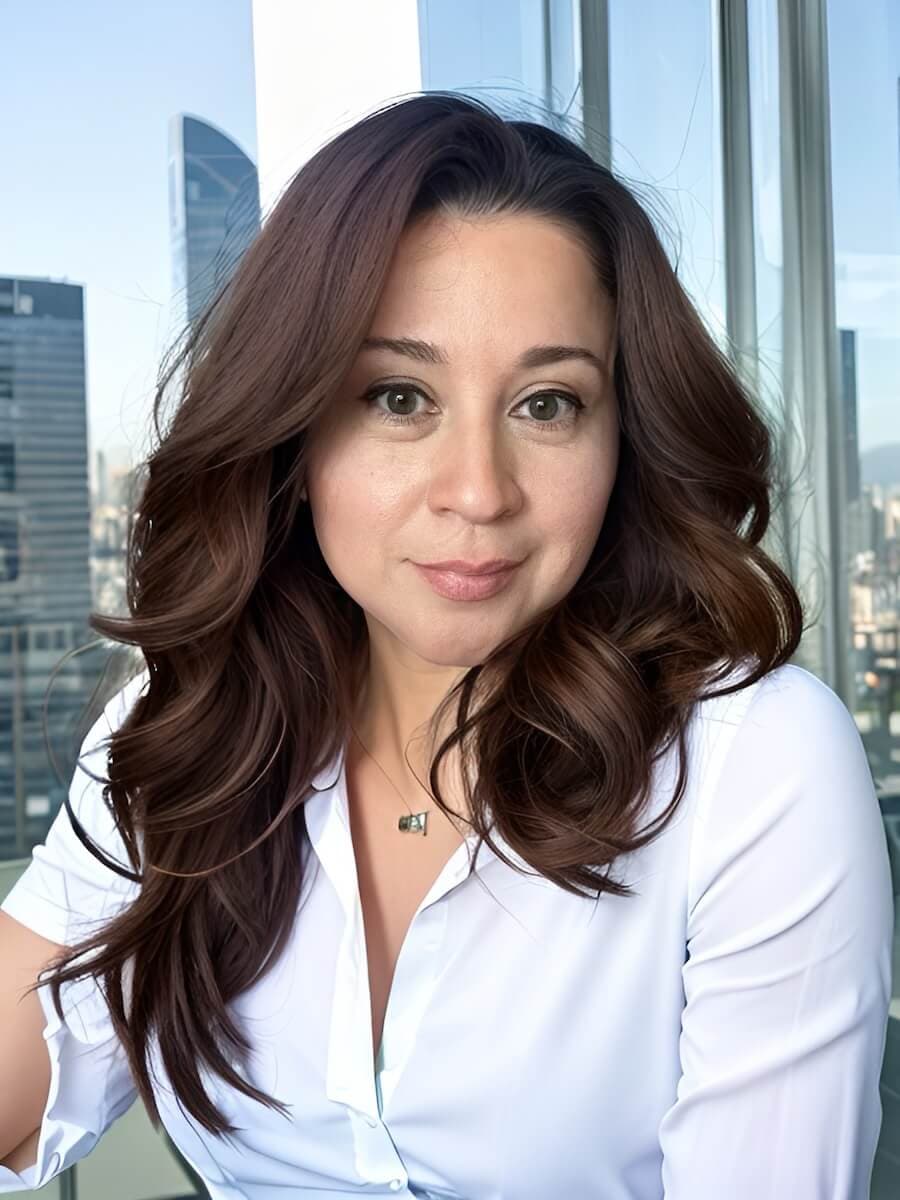 Elida, owner and designer of Season and Sparkle, seated by city windows.