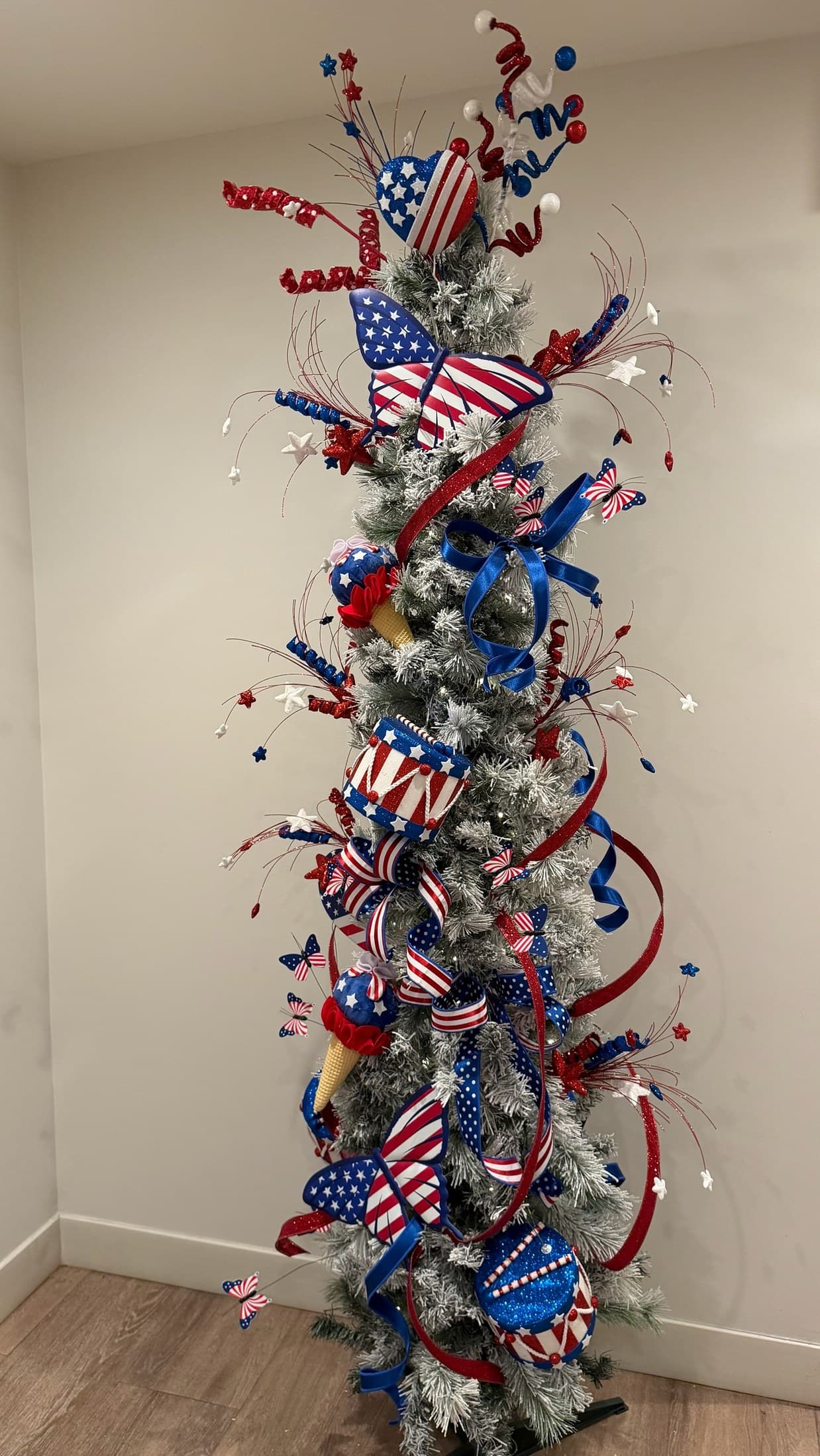 Patriotic pencil tree with red and blue ribbon, white ornaments, and warm lights.