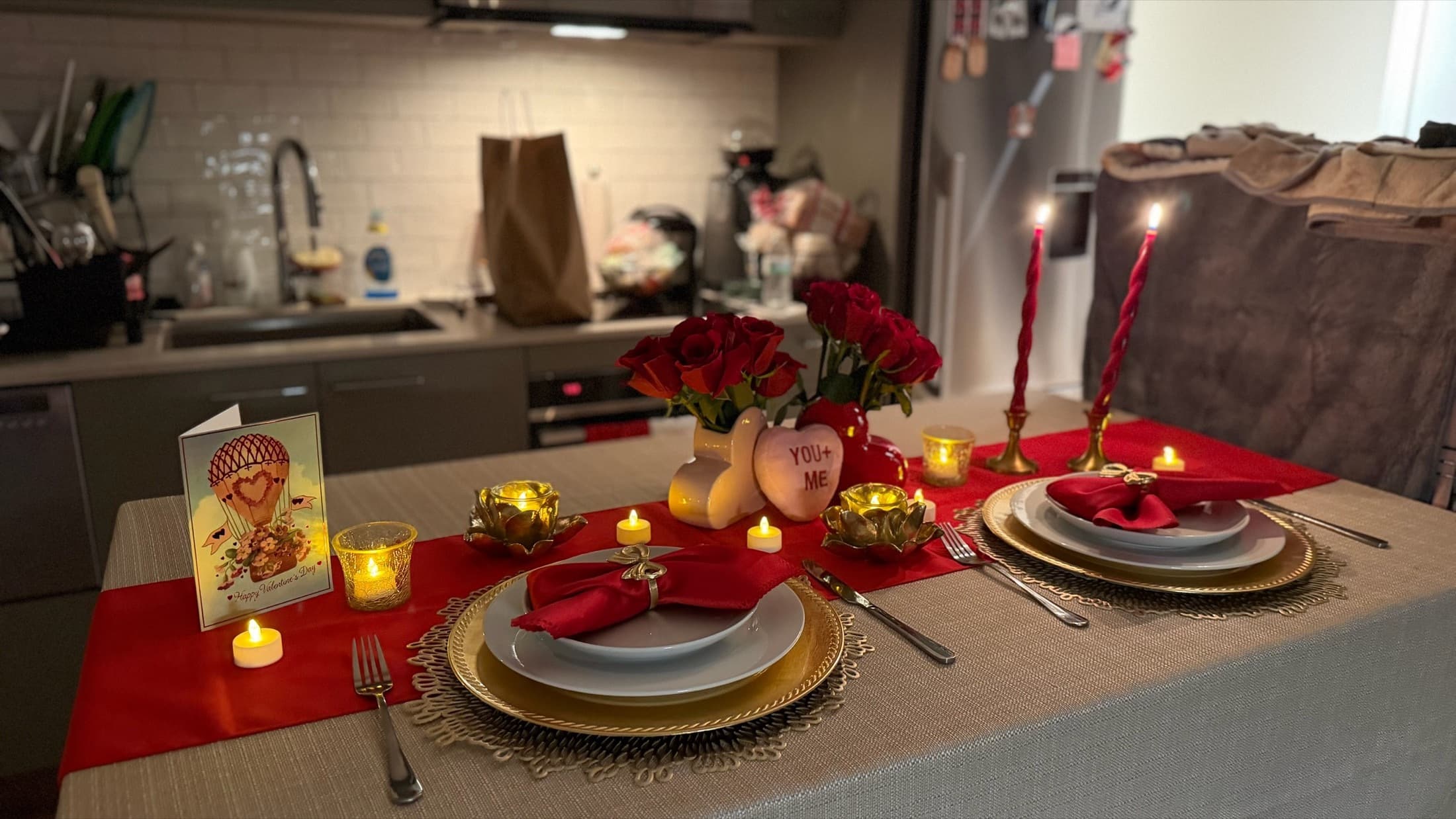 Holiday table setting with red accents, chargers, florals, and layered place settings.
